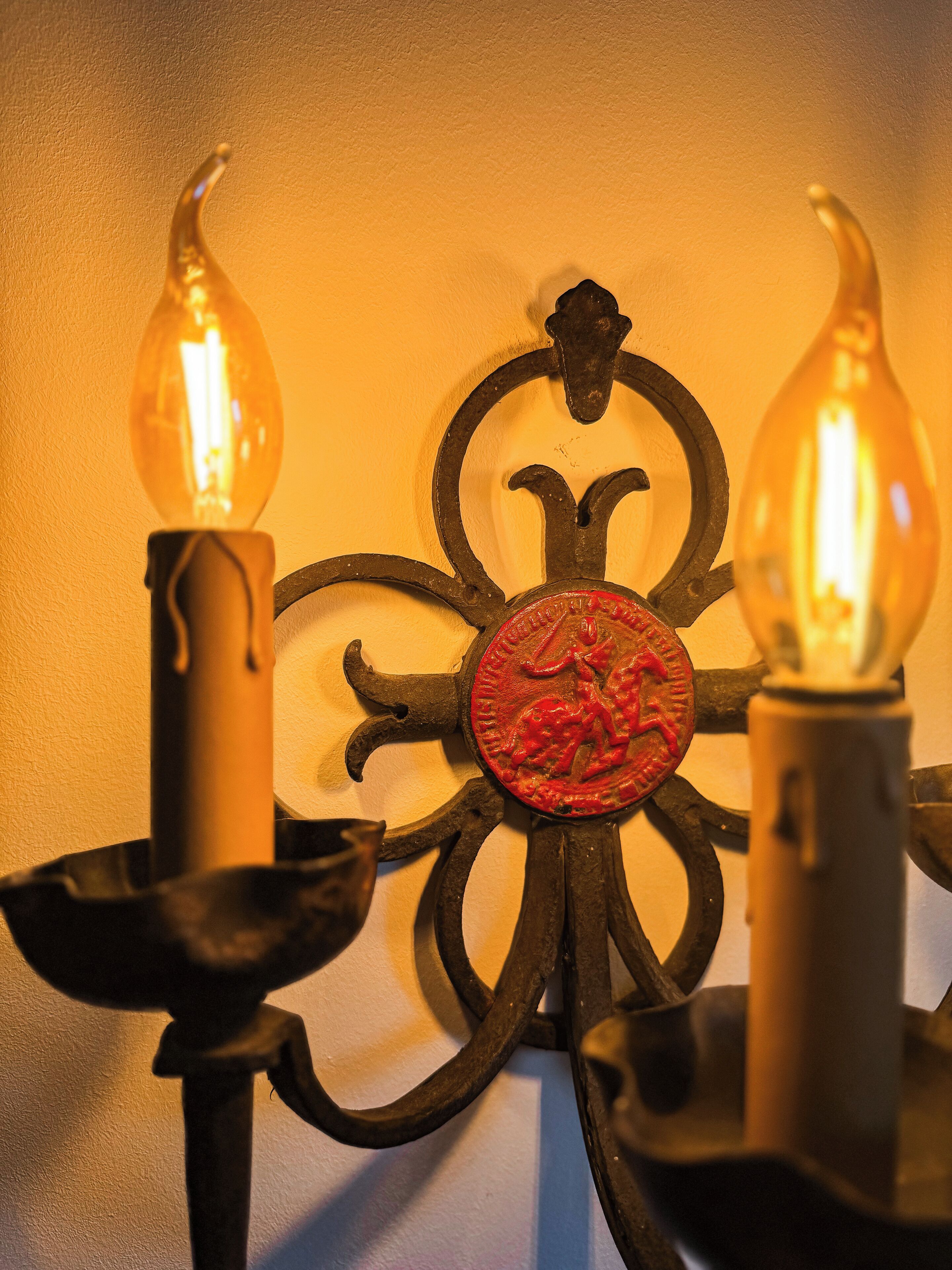A wall-mounted candle holder with two lit candles.