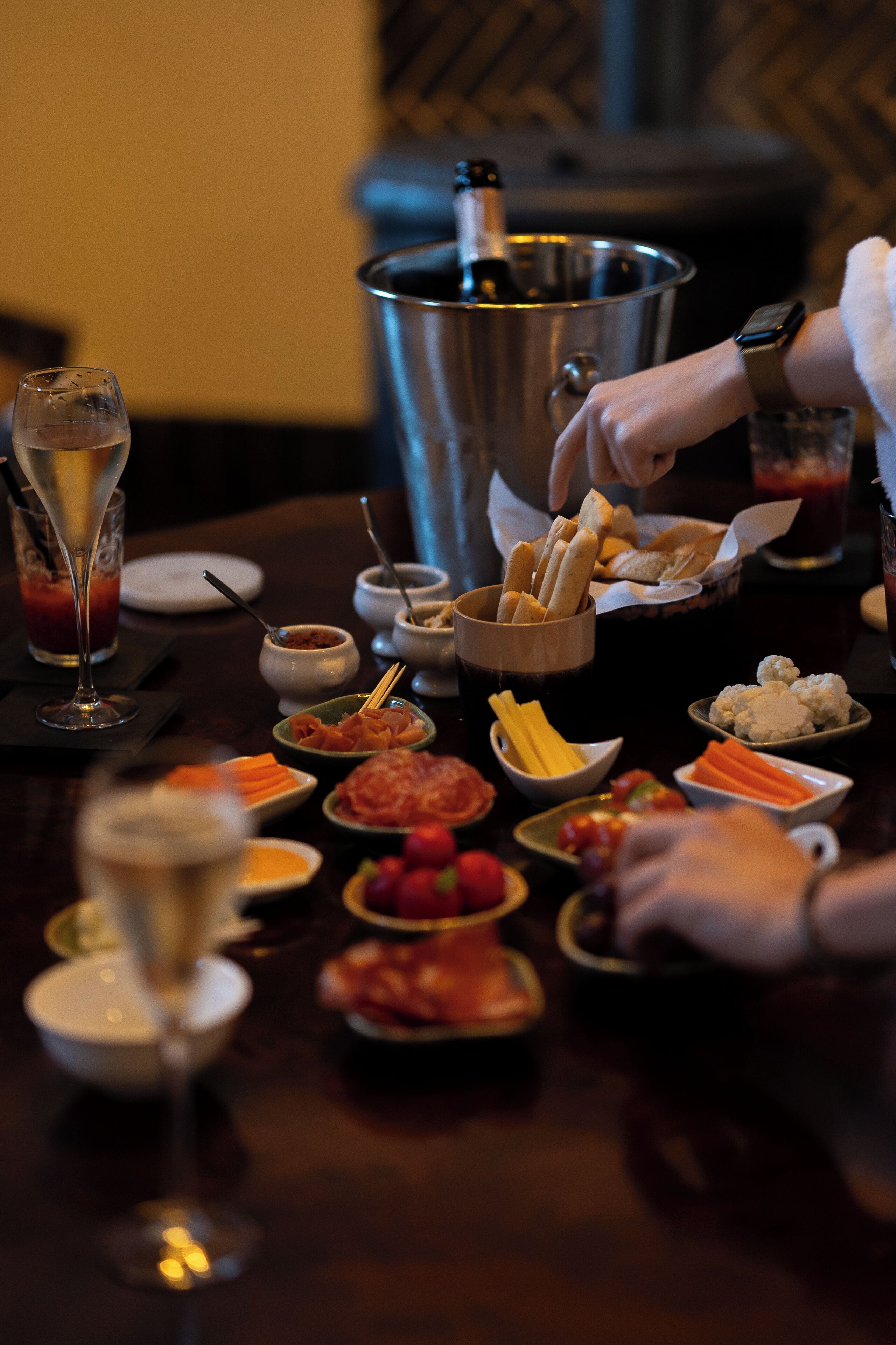 Une table dressée avec divers plats, une bouteille de champagne et un verre de vin rouge.