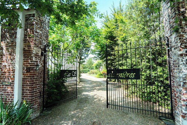 Una entrada portonada a una propiedad con un muro de ladrillo y un letrero que dice "albergoes".