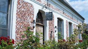 A building with a white facade and red brick walls, featuring arched windows and hanging lanterns.