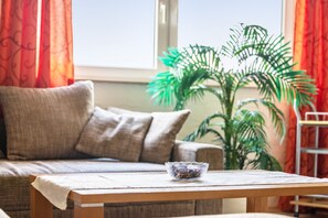 En stue med en sofa, et bord med en skål og en potteplante.