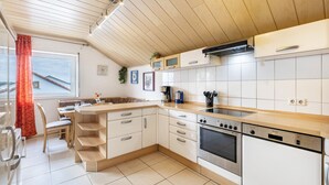 A modern kitchen with white cabinets, a wooden countertop, a built-in oven, and a dishwasher. - Apartment “Haus Fabio” with Private Terrace and Wi-Fi (Engstingen)