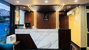 Een hotel receptie met een marmeren balie, houten lambrisering en een klok aan de muur.