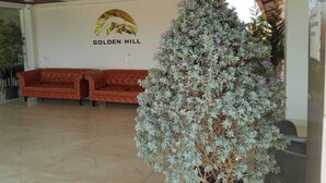 Eine Lobby mit einer großen Kübelpflanze, einem roten Sofa und einer Wand mit dem Schriftzug 'GOLDEN HILL'.