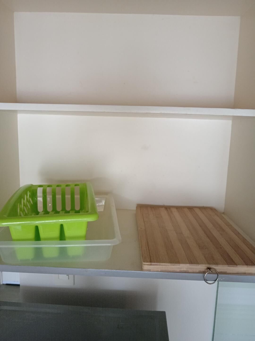 A kitchen with a countertop, a green plastic container, and a wooden cutting board.