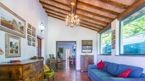 A spacious living area with a blue sofa, wooden furniture, and a tiled floor.