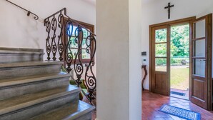 A staircase with ornate metal railings leading to a door with a cross above it.