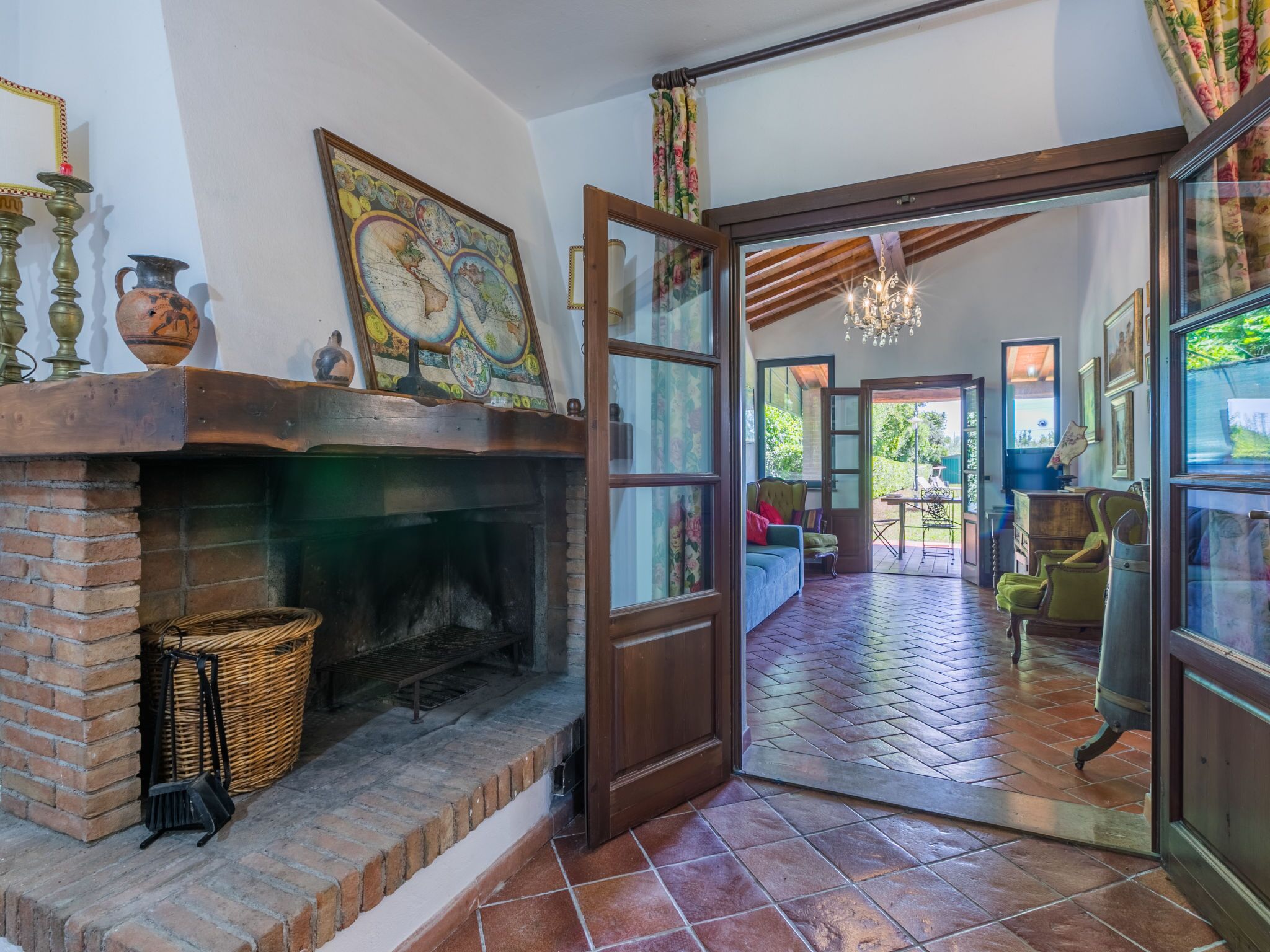 A cozy room with a brick fireplace, a large window, and a view of the garden.