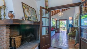 A cozy room with a brick fireplace, a large window, and a view of the garden.