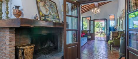 A cozy room with a brick fireplace, a large window, and a view of the garden.