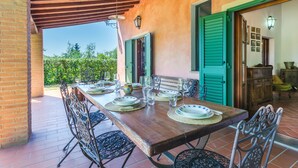 An outdoor dining area with a wooden table set for four, surrounded by metal chairs.