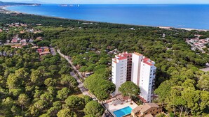 A high-rise hotel with a swimming pool, surrounded by dense greenery and a coastal view. - Beautiful apartment with spectacular views, pool and close to the beach! (Pals)