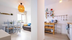A modern kitchen with wooden shelves, a dining area with a white table and blue chairs, and a bright pendant light. - Beautiful apartment with spectacular views, pool and close to the beach! (Pals)