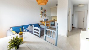 A modern kitchen with white cabinets, a wooden table, and a hanging orange pendant light. - Beautiful apartment with spectacular views, pool and close to the beach! (Pals)