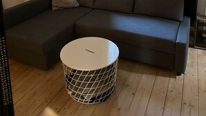 Ein modernes Wohnzimmer mit einer Eckcouch, einem runden Couchtisch und einem kleinen Beistelltisch.