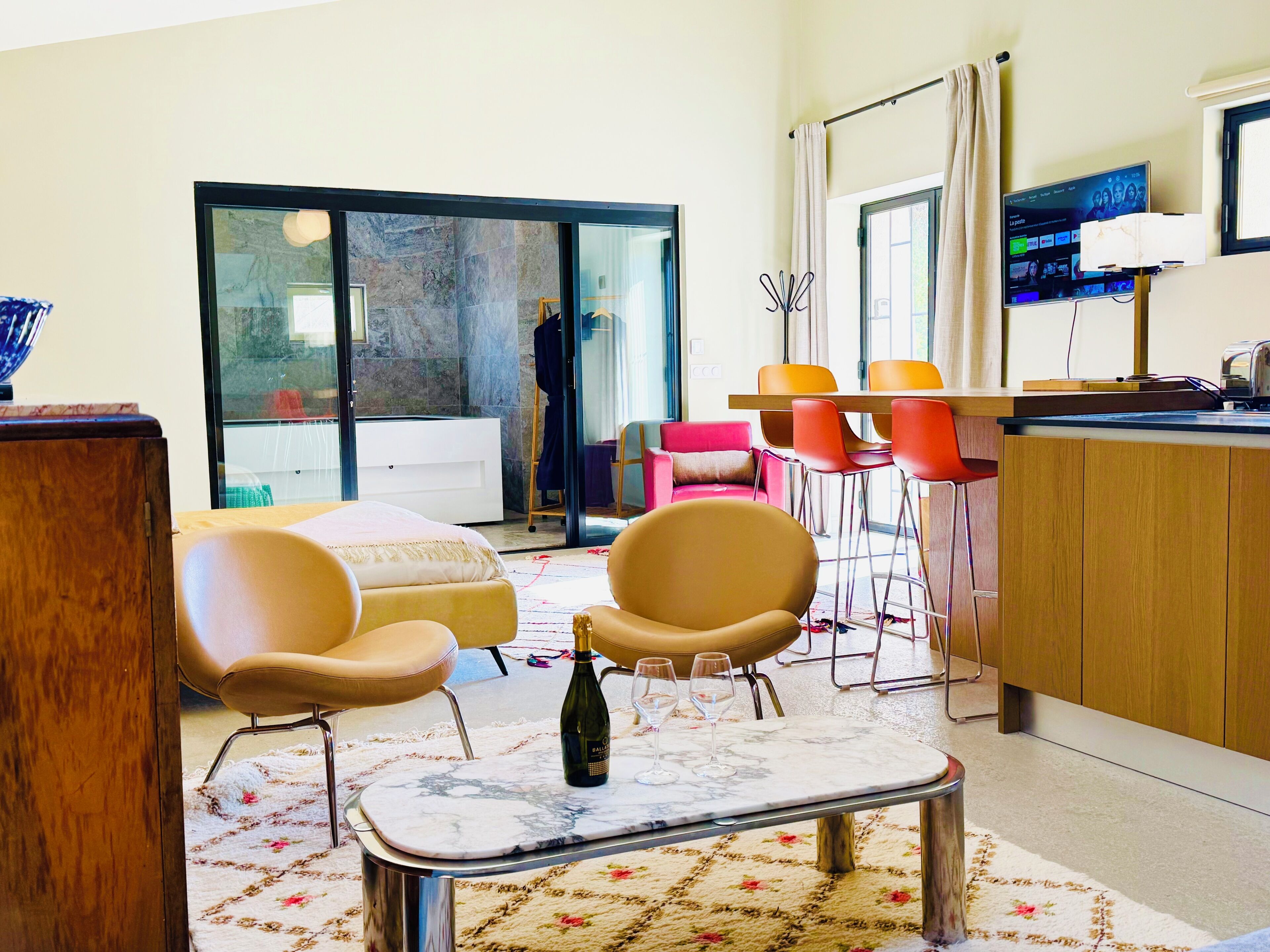 A modern living room with a sofa, chairs, a dining table, and a kitchen area with a TV.