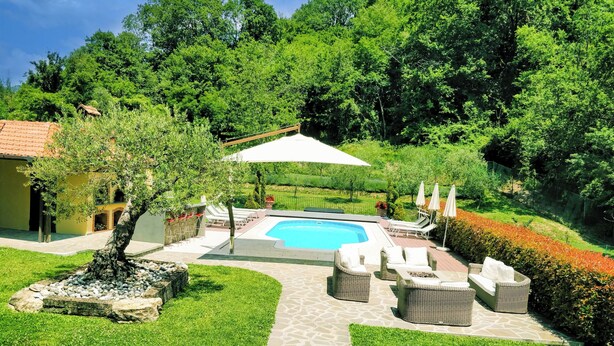 A backyard with a swimming pool, outdoor furniture, and a garden.