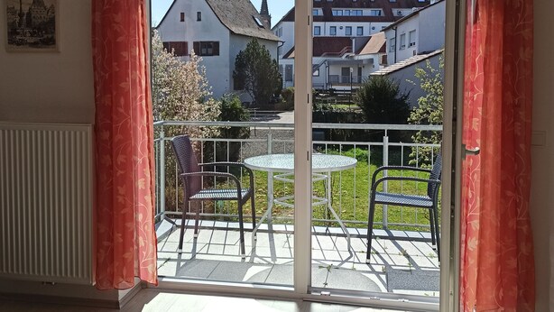 A balcony with a table and chairs, a view of neighboring houses, and a radiator. - Rottenburg City 4 rooms with cathedral view (Rottenburg)