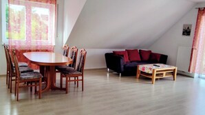 A room with a dining table, chairs, a sofa, and a small table with a floral tablecloth. - Rottenburg City 4 rooms with cathedral view (Rottenburg)