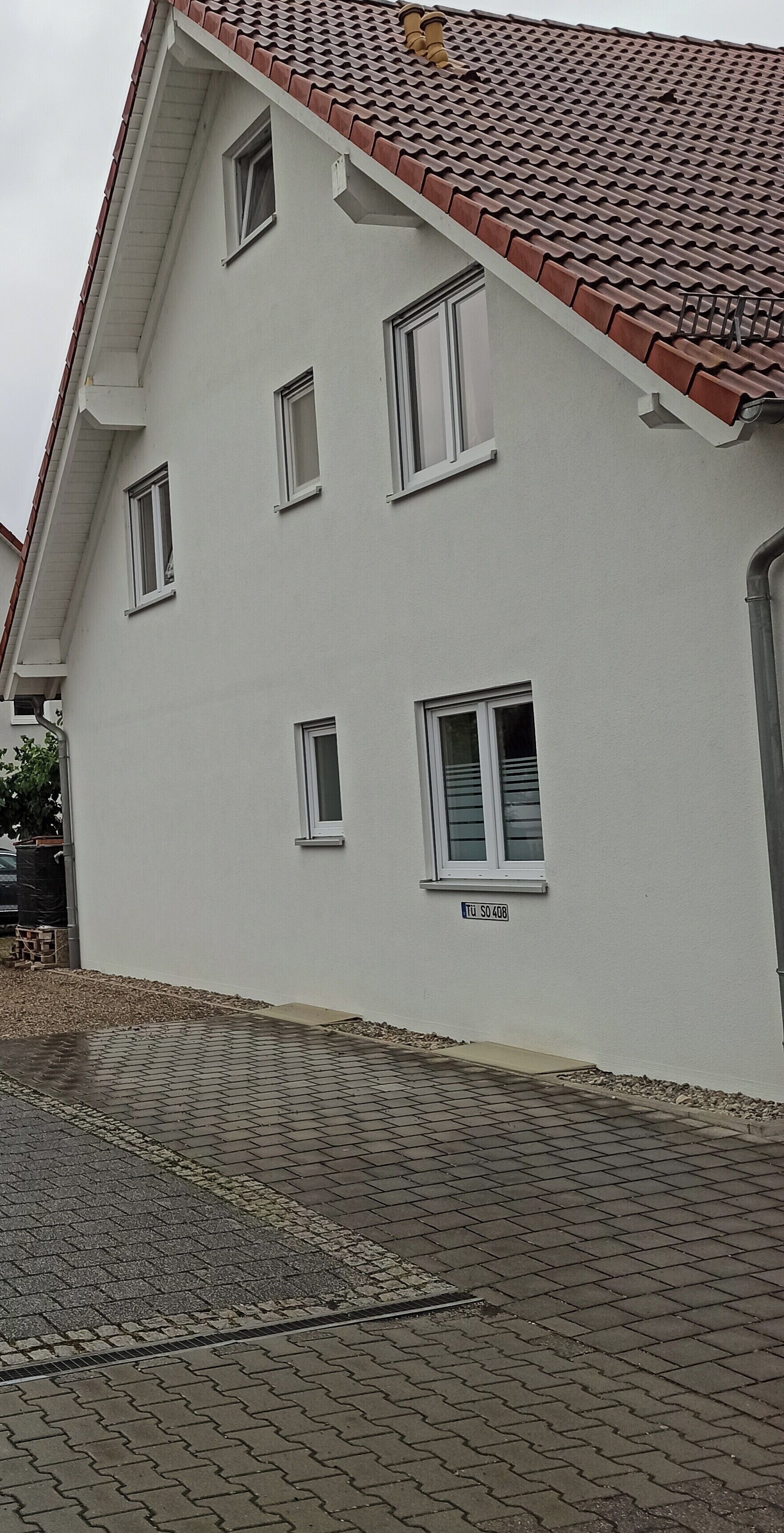 Ein zweistöckiges Gebäude mit Ziegeldach, zahlreichen Fenstern und einer gepflasterten Auffahrt.