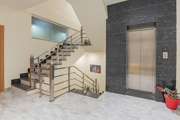 A modern interior with a marble staircase, a wall-mounted artwork, and a marble elevator.