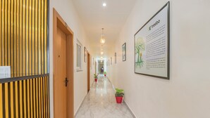A hallway with wooden doors, potted plants, and framed artwork on the walls. - Treebo Gaur Vasundhara (Vrindavan)