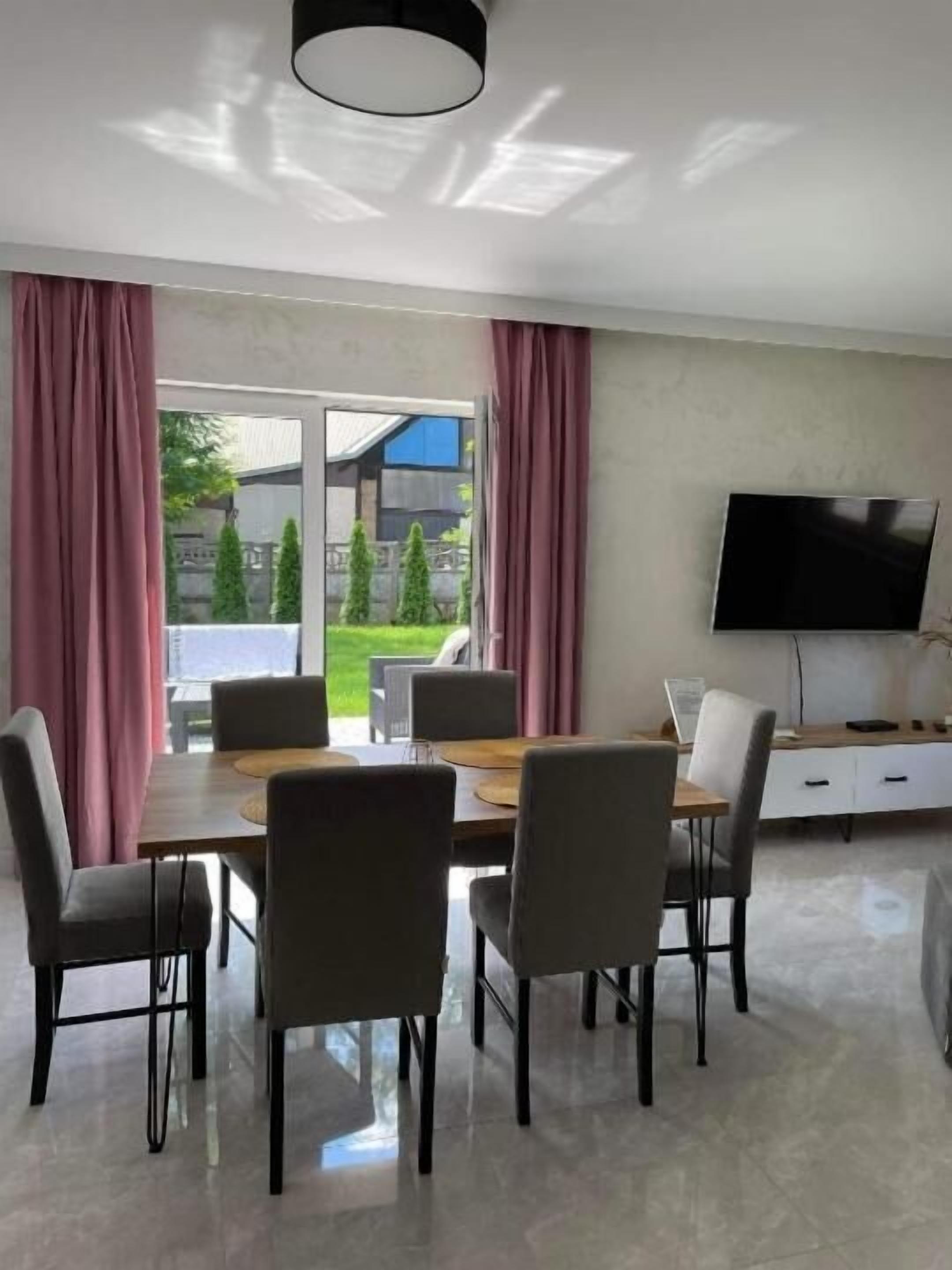 Un comedor moderno con una mesa, sillas, un televisor de pantalla plana y vistas a un jardín.