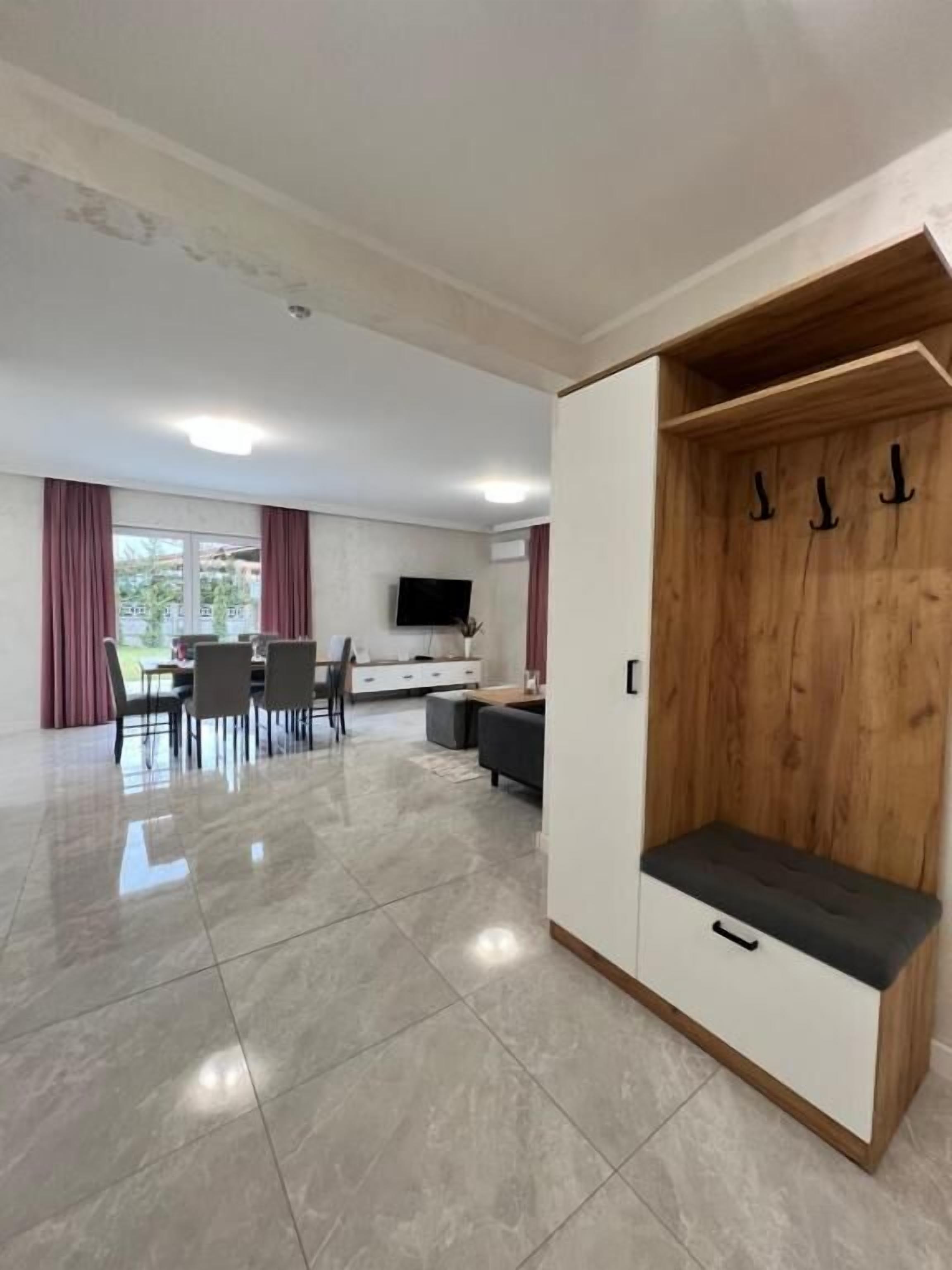 Un'ampia zona giorno con un tavolo da pranzo, una TV a parete e un armadietto in legno con ganci.