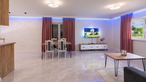 A modern living room with a TV, a dining table, and a sofa. - Apartamenty Max House (Zator)