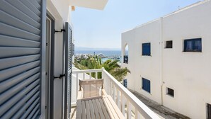 A balcony with a view of the sea and boats, white buildings with blue shutters, and a clear sky. - Phaedrus Living: Paros Cycladic Residences 8 (Paros)