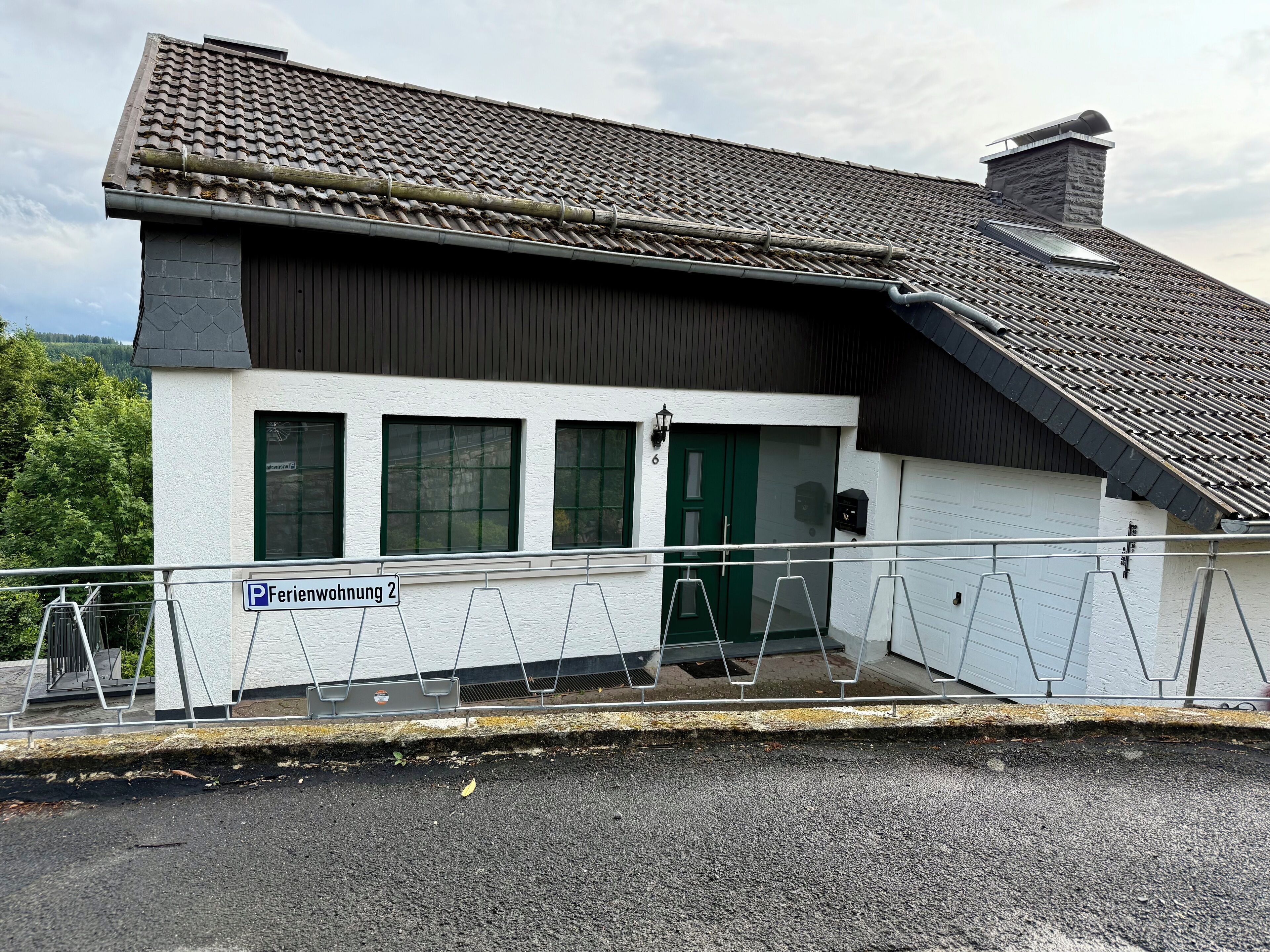 Un bâtiment avec un toit recouvert de tuiles, une porte verte et une enseigne indiquant « Appartement de vacances n° 2 ».