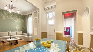 A living room with a glass coffee table, a sofa, and a dining table with a book and lemons. - Live in Athens PANGRATI Fine Residence (Athens)