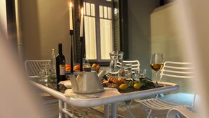 A table set for two with a bottle of wine, glasses, a pitcher, and a plate of food. - Live in Athens PANGRATI Fine Residence (Athens)