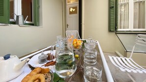 A dining table set with a pitcher of water, glasses, a bowl of fruit, and a teapot. - Live in Athens PANGRATI Fine Residence (Athens)
