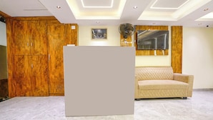 A room with a wooden wardrobe, a beige sofa, and a large mirror on the wall. - Crystal By Glitz Hotels (Mumbai)