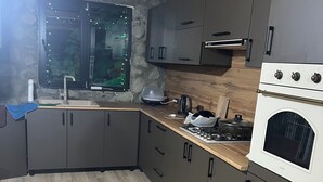 A kitchen with a stone wall, wooden ceiling, and a built-in oven. - Cloudnestbakhmaro (Bakhmaro)