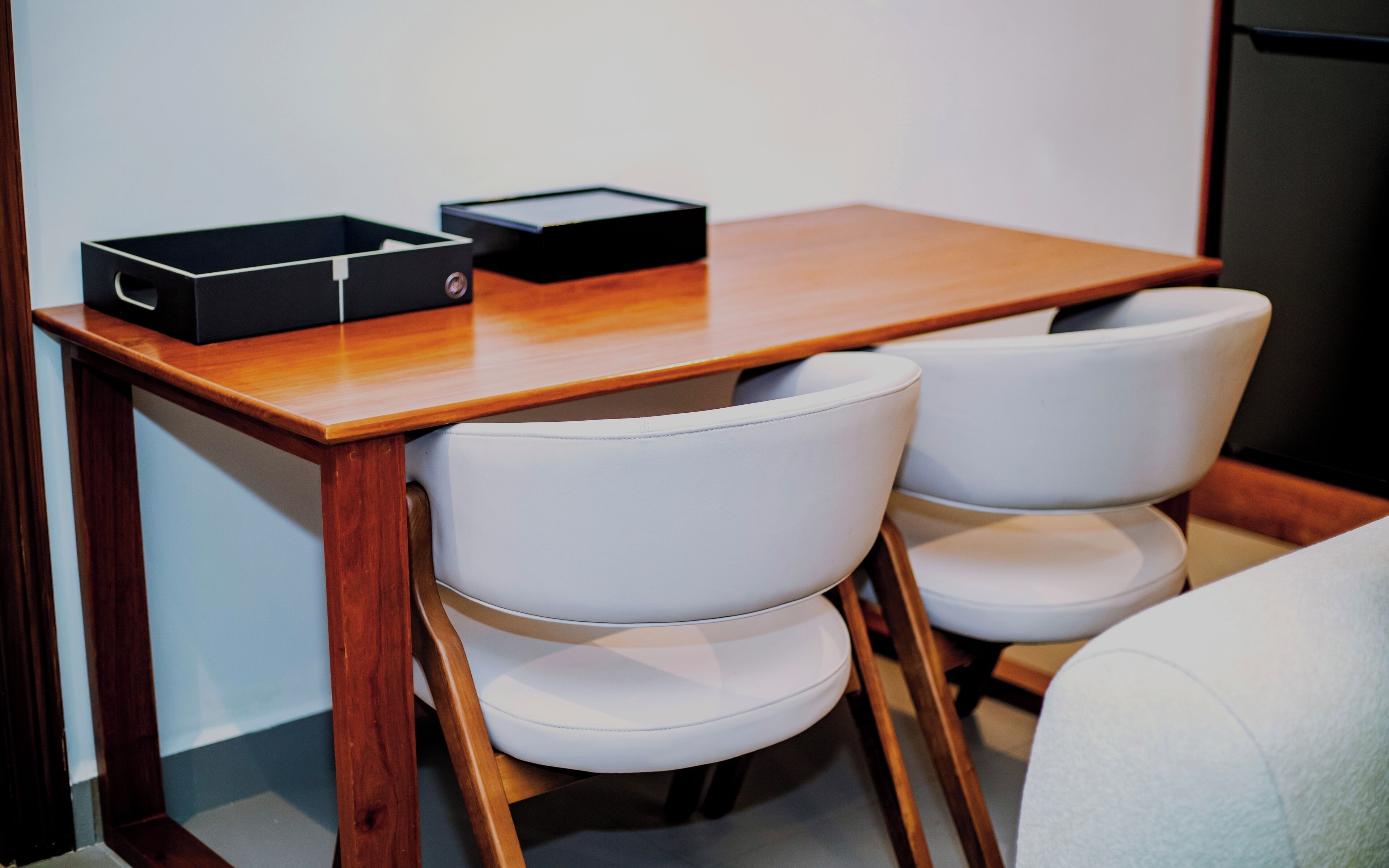 Een houten tafeltje met twee witte stoelen.
