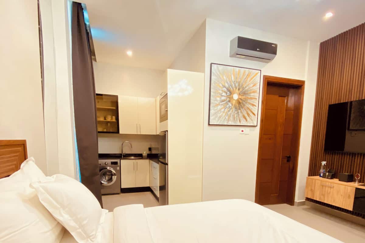 Une chambre d’hôtel équipée d’un lit, d’une kitchenette, d’une télévision et d’un luminaire décoratif au plafond.