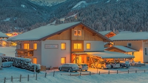 A hotel with a wooden facade, multiple balconies, and a covered parking area. - Family and pet-friendly apartment in beautiful Flachau. (Flachau)