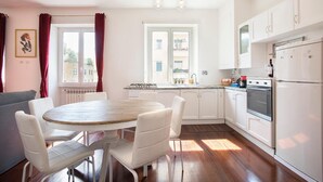 A modern kitchen with white cabinets, a dining table with chairs, and a stove.