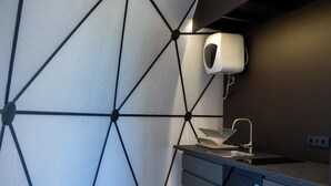 Uma cozinha moderna com design geométrico na parede, lava-louças embutida e dispensador de papel toalha.