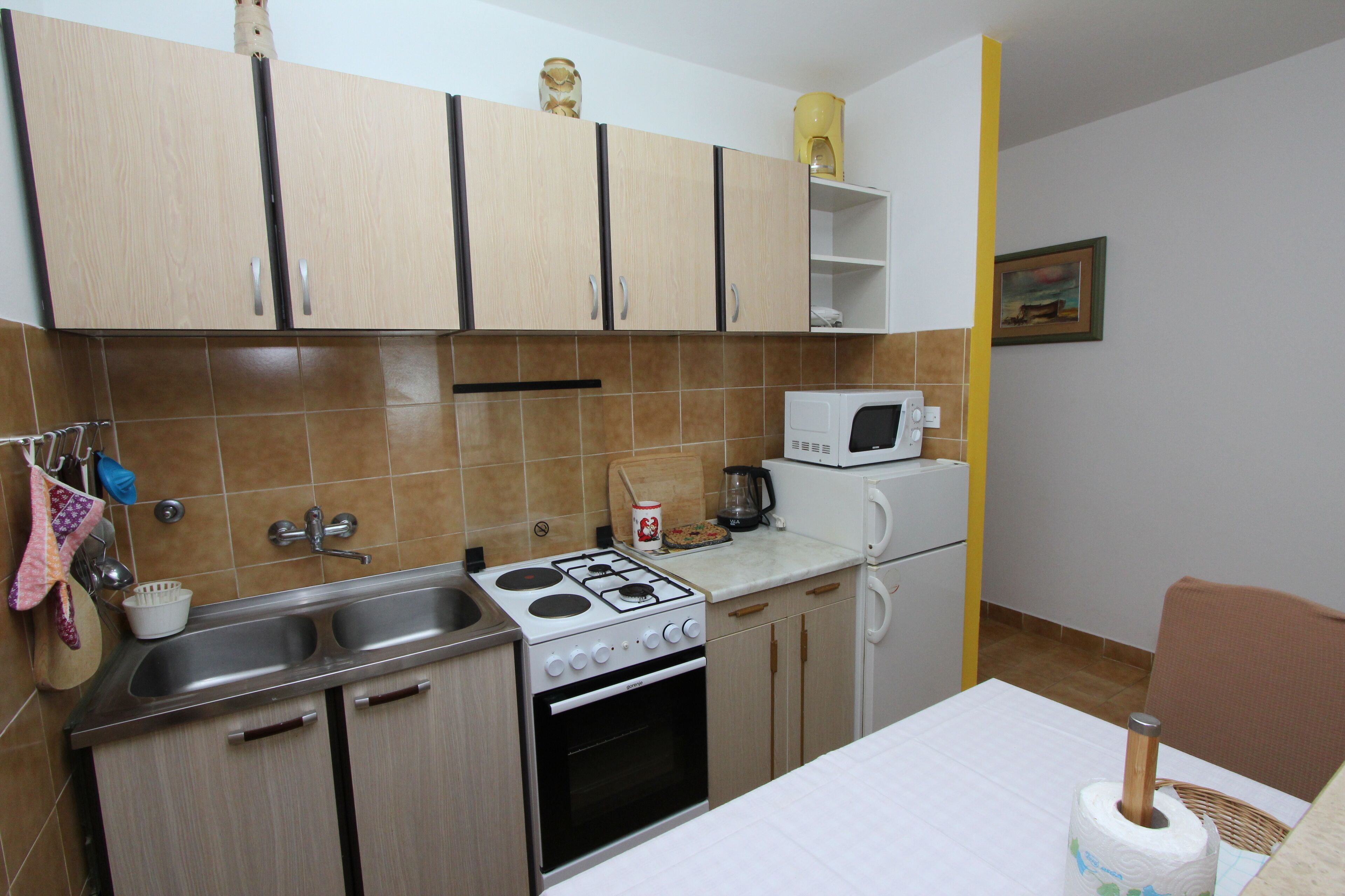 Cocina compacta con estufa, fregadero, microondas y un pequeño comedor.