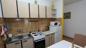 A compact kitchen with a stove, sink, microwave, and a small dining area. - Studio Vera (Rovinj)
