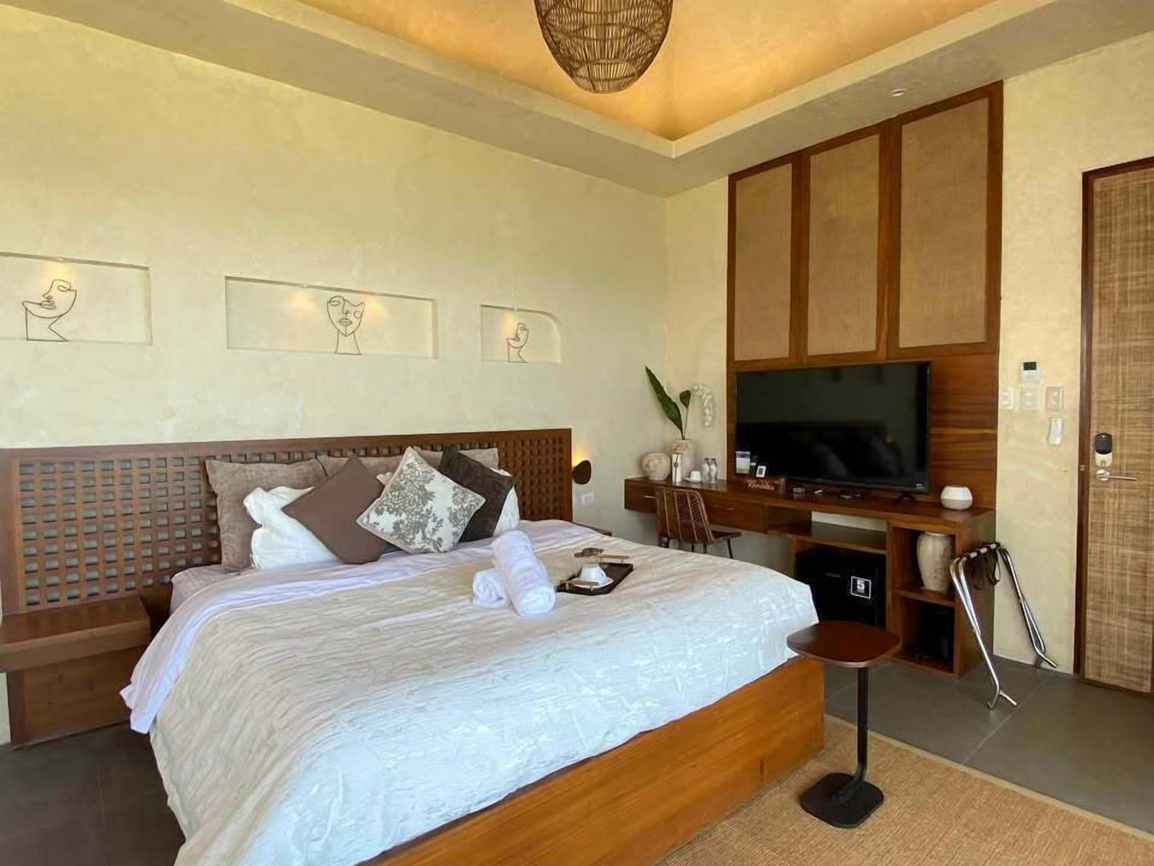 A modern bedroom with a large bed, a TV, and a desk area.