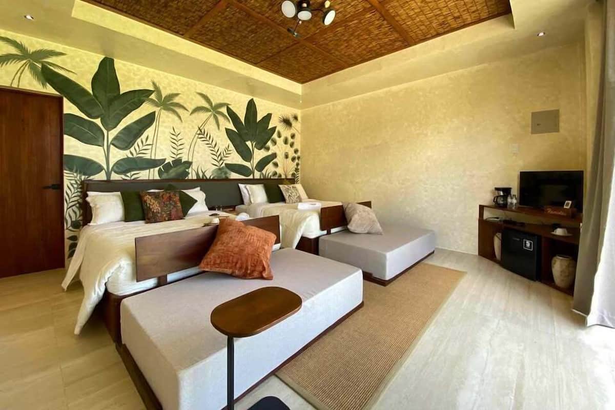 Een ruime slaapkamer met een groot bed, twee banken, een televisie en een plafondventilator.