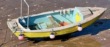 Uma pequena embarcação com interior azul, exterior amarelo e verde, e dois boias.