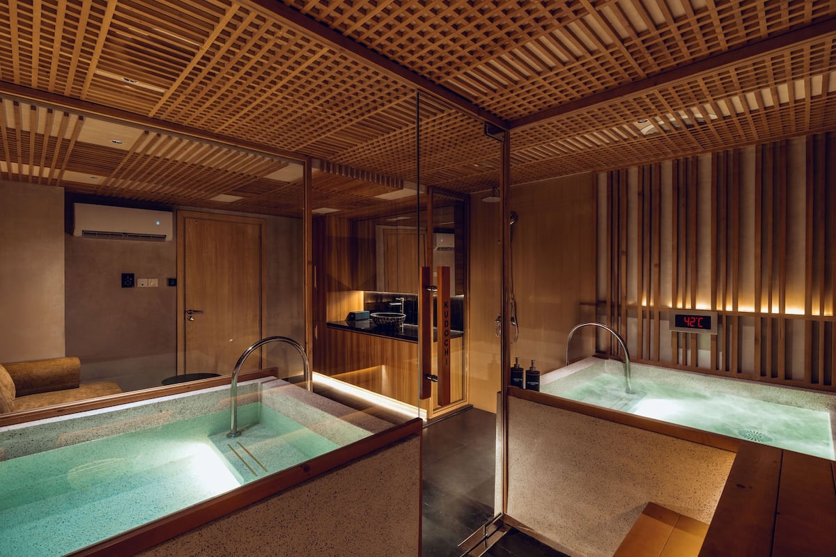 A spa area with a large soaking tub, wooden ceiling, and a digital thermometer.