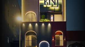 A hotel with a prominent 'KIND' sign, large arched windows, and a well-lit entrance. - KiN Hotel Onsen  (Ho Chi Minh City)