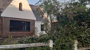 Een modern huis met een schuin dak, een groot raam en een houten omheining.
