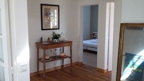 Een kamer met een houten console tafel, een lijst met foto en een bed op de achtergrond.